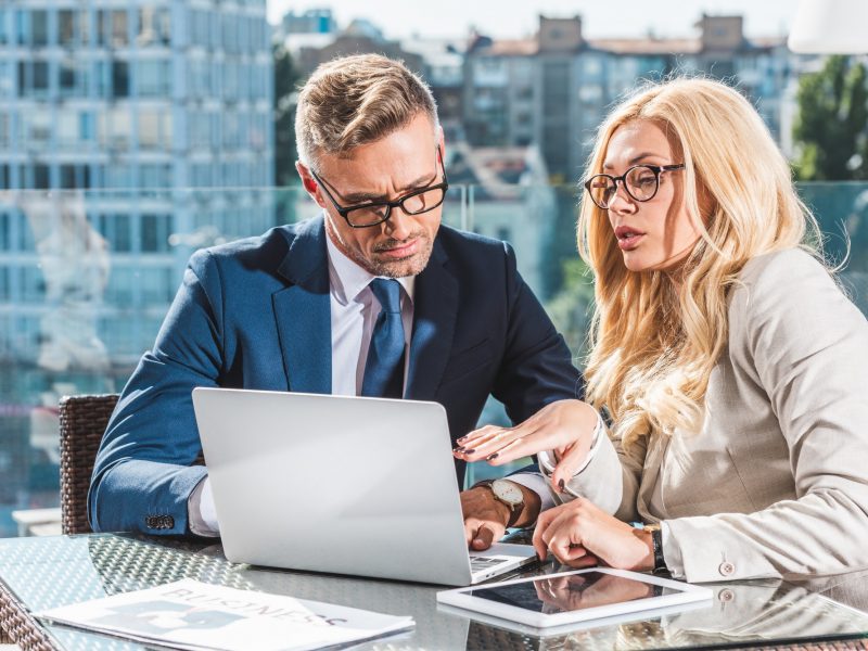 confident business colleagues using laptop during business meeting in cafe